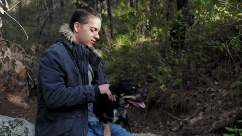 Man pets his dog in the forest