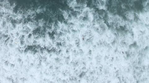 Aerial view of the sea and people surfing Aerial view of waves and surfers on their surfboards.