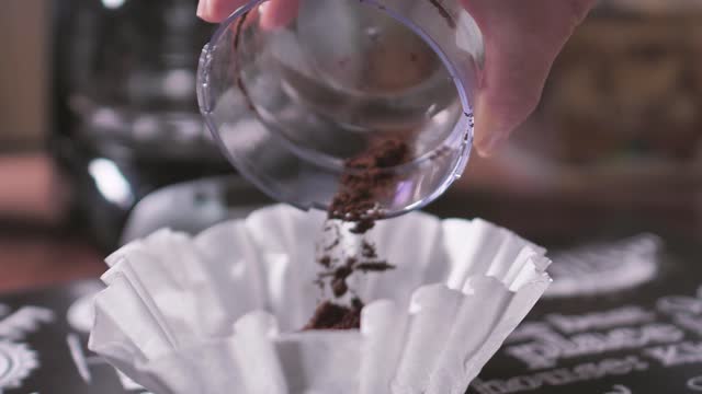 Coffee powder being poured on the coffee maker filter