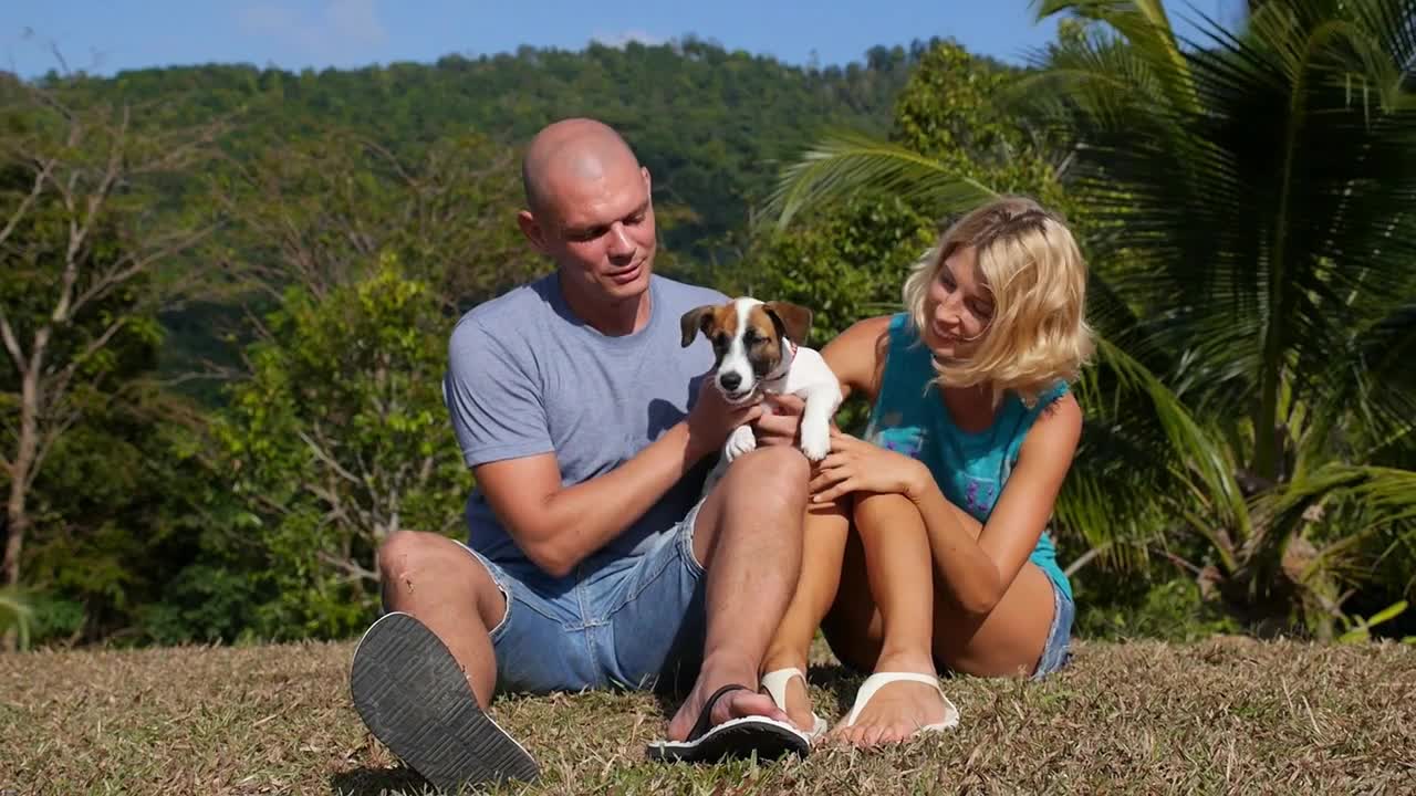 Happy Couple Holding a Puppy Dog Outdoors