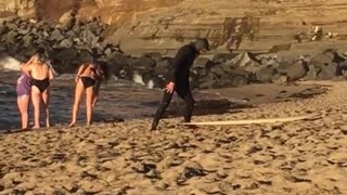 Guy in black wet suit laying on yellow surf board