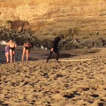 Guy in black wet suit laying on yellow surf board