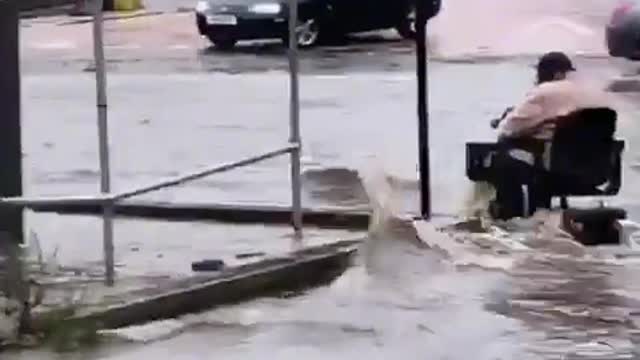 Fearless person on a motorized scooter during a flood