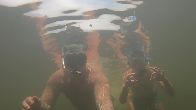 Scared son with fake shark under water