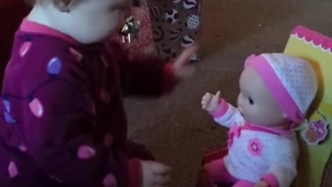 Playful baby has precious reaction to new doll