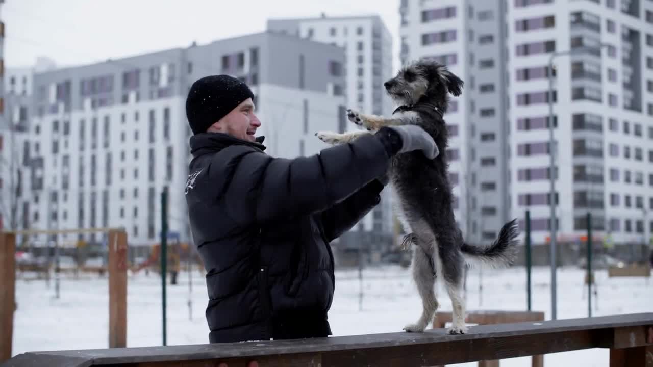 Male owner training dog on playground at winter city