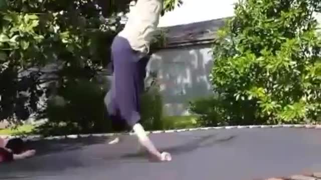 Boy in blue shirt does flip on trampoline lands on shoulder