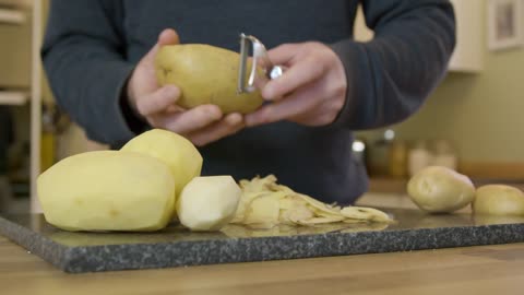 Tracking In Man Peeling Potatoes in Kitchen