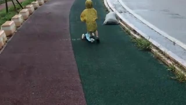 Children riding a kickboard on a rainy day
