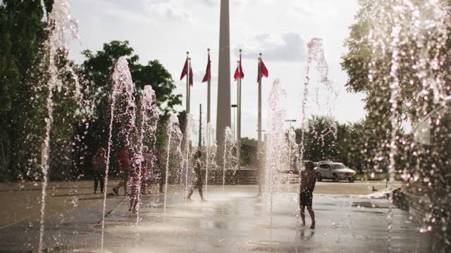 slow motion footage of children and adults playing in the water fountains