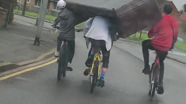 Squad of Cyclists Carry a Couch