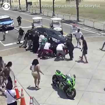 Onlookers & Police Come to the Rescue of Motorcyclist Trapped Beneath a Car