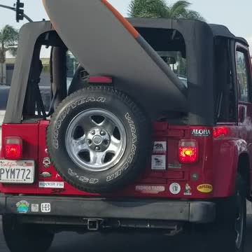Red jeep car with surf board outside