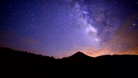 Stardust and clouds over mountains at night