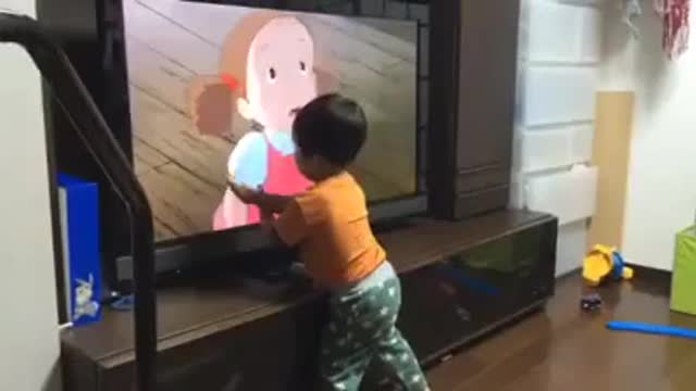 Little Asian kid watching cartoons and interacting with it