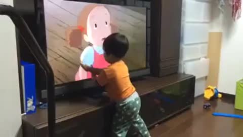 Little Asian kid watching cartoons and interacting with it