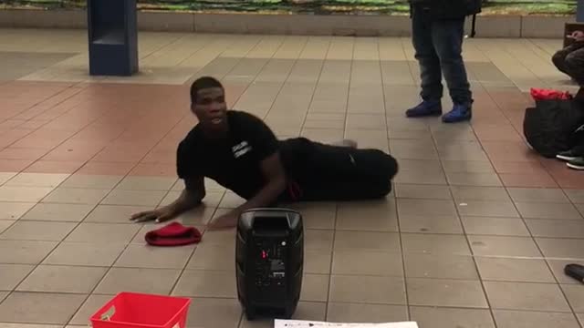 Man in black outfit red beanie dancing subway station