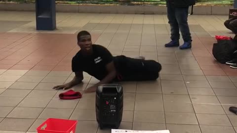 Man in black outfit red beanie dancing subway station