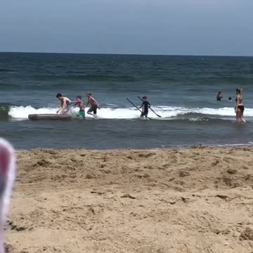 Kids playing with grey mattress at beach