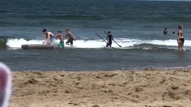 Kids playing with grey mattress at beach