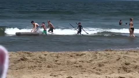 Kids playing with grey mattress at beach