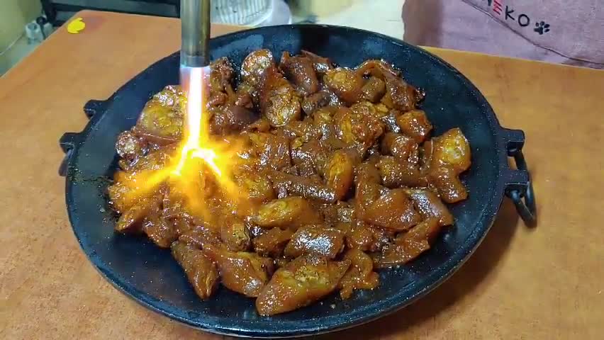 Grilling pork with a torch on an iron plate