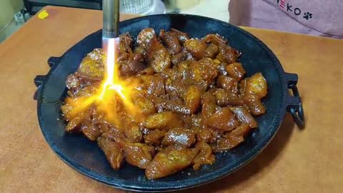 Grilling pork with a torch on an iron plate