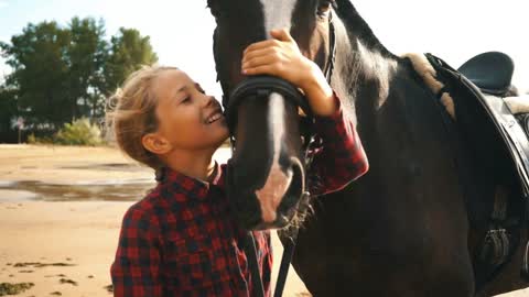 Beautiful girl cares for her horses on beach. Focus on the girl