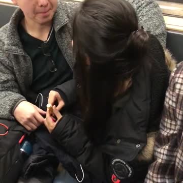 Girlfriend applies chapstick on boyfriends lips who tries to kiss her on subway