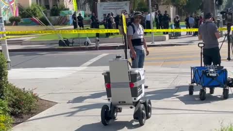 A food delivery robot forces it’s way across a police crime scene