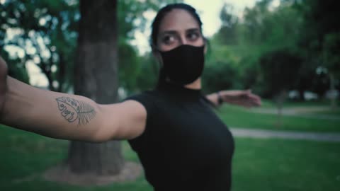 Woman with face mask stretching with her arms in a park