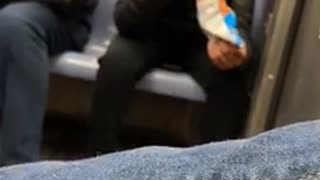 Woman wearing airpods sucks on her cheeto puffs on subway train