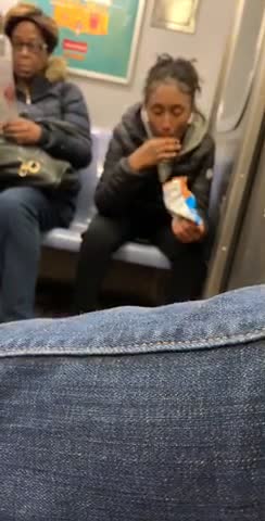 Woman wearing airpods sucks on her cheeto puffs on subway train