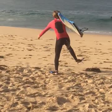 Teen in red wetsuit blue snorkeling shoes runs on beach