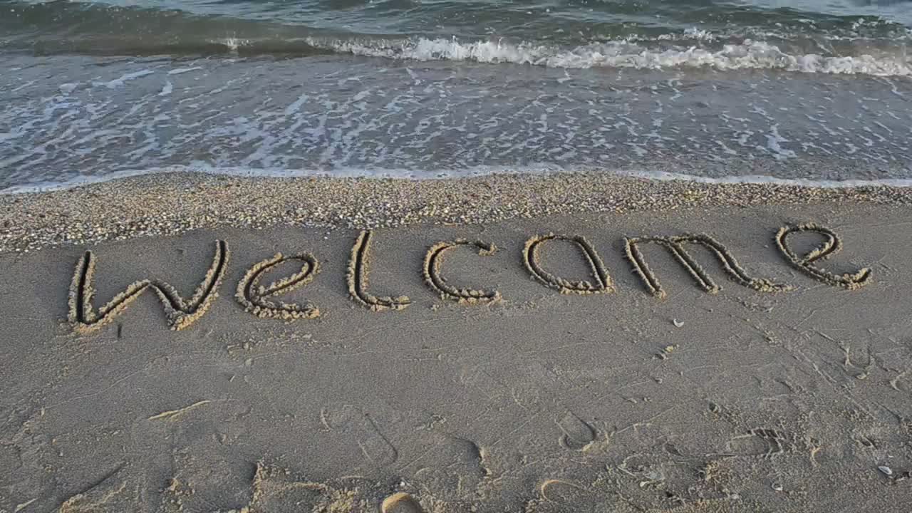 "Welcome" in the sand at the seashore