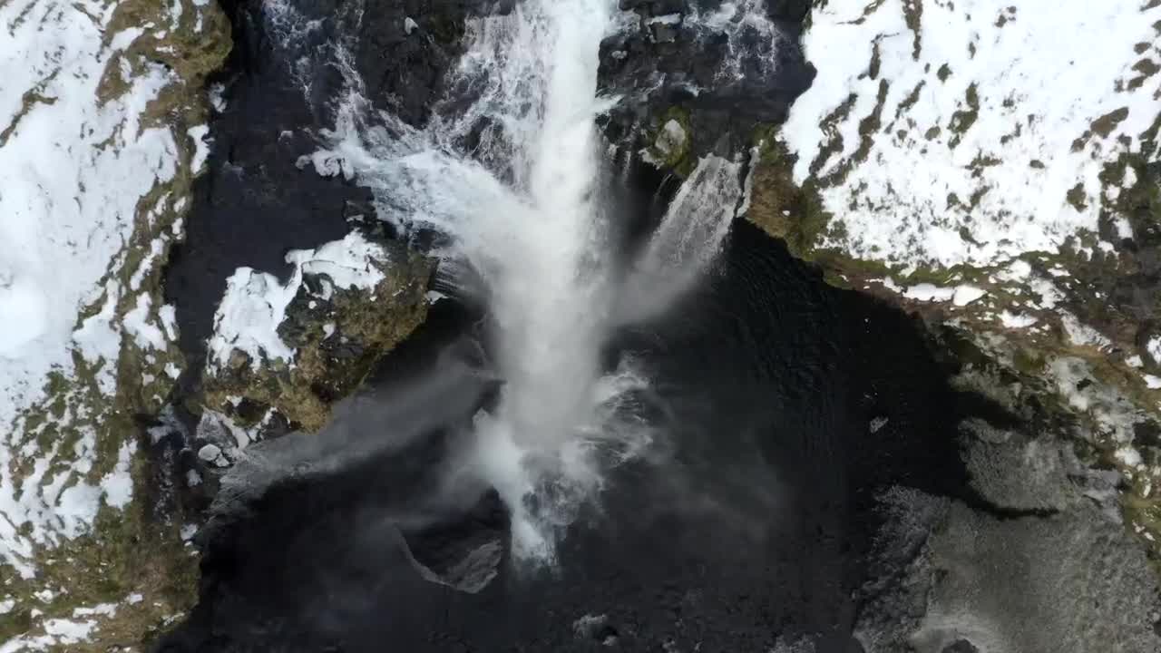 Top aerial shot of a waterfall in a winter forest