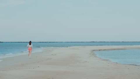 Girl running on sea beach toward sea