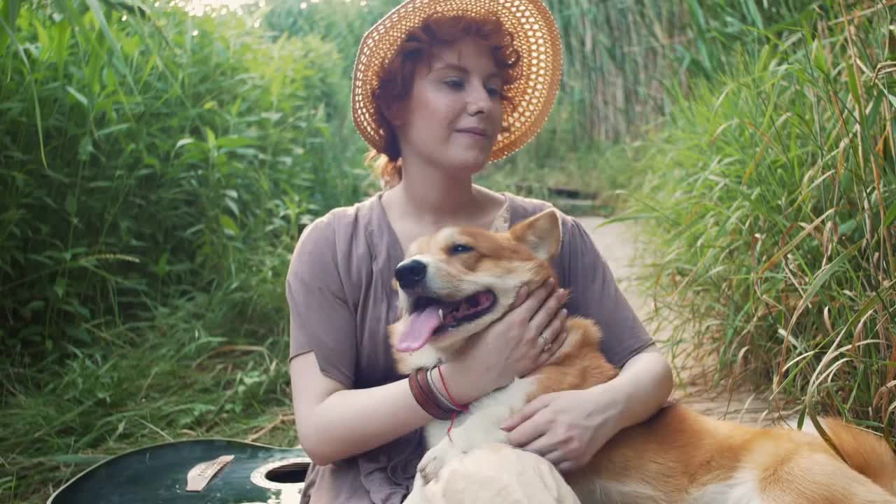 Happy corgi dog with the owner girl in the park near the reed