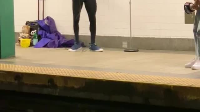 Man dressed in batman costume singing in train station