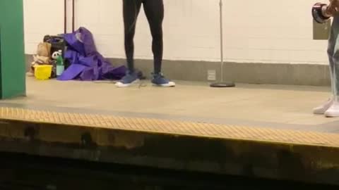 Man dressed in batman costume singing in train station