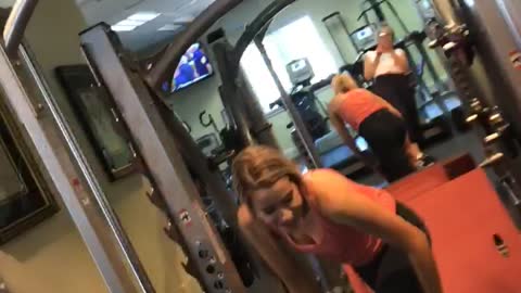 Girl orange shirt doing squats drops weights