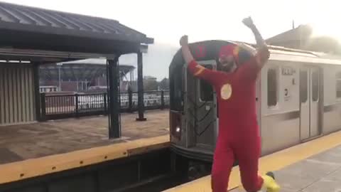 Man in red flash costume running next to subway train