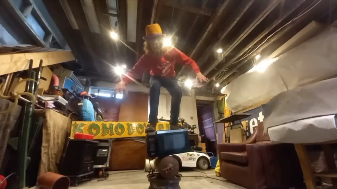 Man Balances on a Stack of a Car Rim, Fire Extinguisher and a Microwave