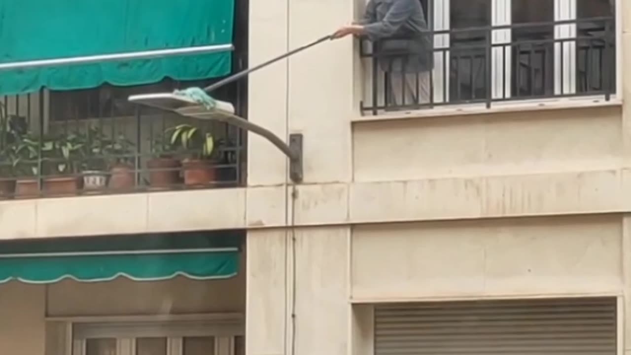 Woman Scrubs Lamppost from Her Apartment Window