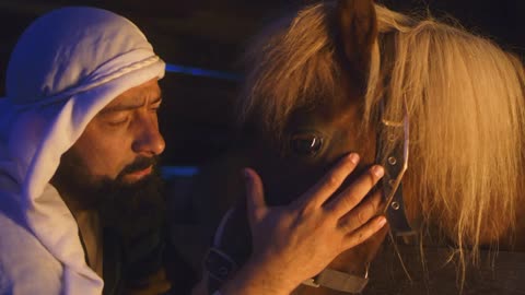 man touching head of horse and talking about Jesus Christ birth in obscure inn stable in Bethlehem