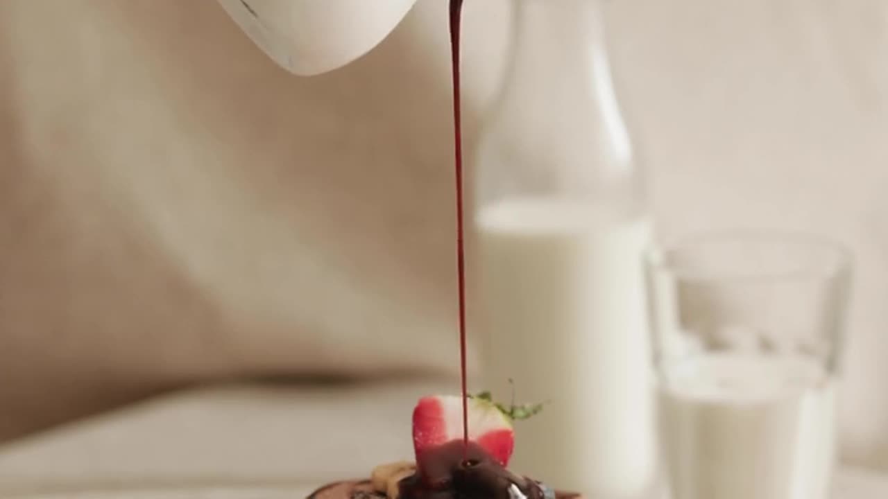 A Person Pouring Chocolate Syrup on Pancakes