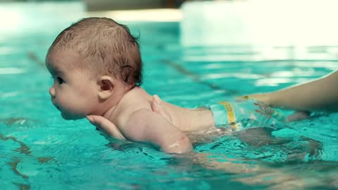 Teaching a baby to swim in the pool