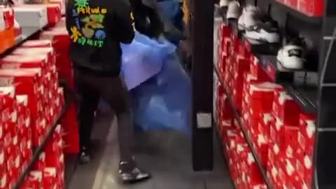 Large group of people stealing sneakers and apparel from a Nike store