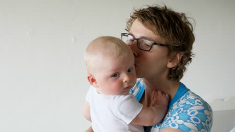 Happy mother holds and kisse baby on white background