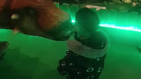 A baby kissing a dinosaur.